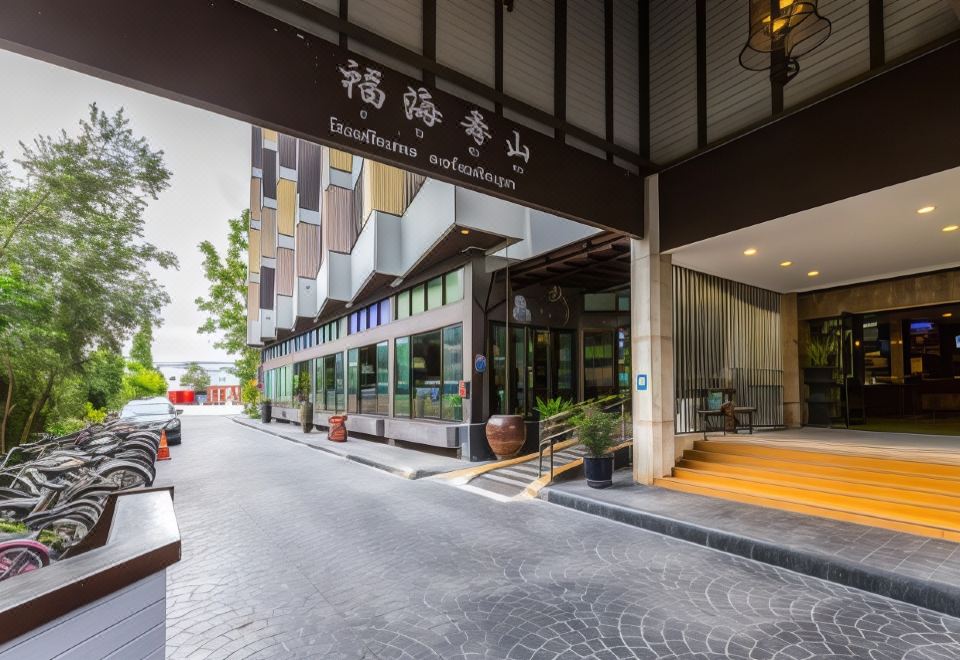 a modern building with a large glass entrance , surrounded by trees and cars parked on the street at Soho Boutique Hotel