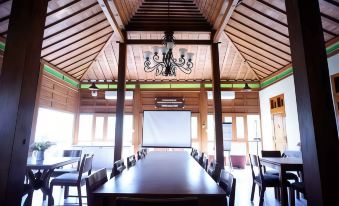 a large wooden dining table surrounded by chairs in a room with a projector screen at Griya Gendhis Saraswati