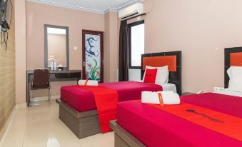 a hotel room with three beds , two of which are twin beds and one is a double bed at RedDoorz Plus @ Paal 2 Manado