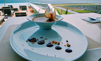 a blue plate with an apple on it is placed on a dining table , overlooking the ocean at Pedras do Mar Resort & Spa