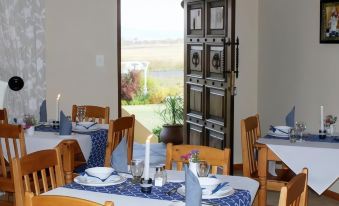 a restaurant with wooden tables and chairs , blue tablecloths , and white napkins set for dinner at Mountain View Guest House