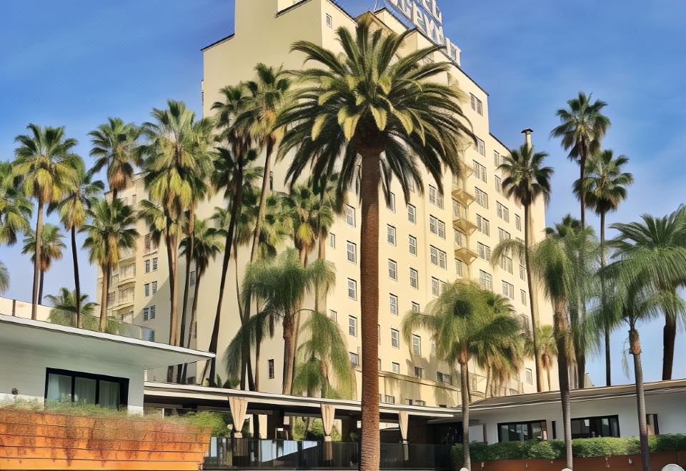 a hotel with a large pool surrounded by palm trees and lounge chairs , creating a tropical atmosphere at The Hollywood Roosevelt