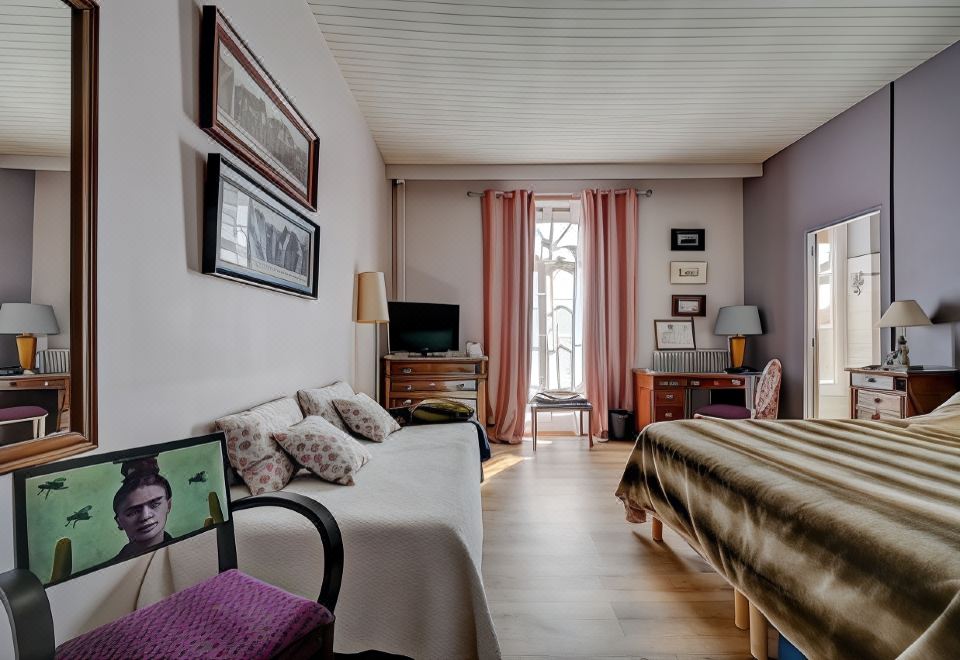 a bedroom with a bed , couch , and television in front of a window with pink curtains at Hotel des Artistes