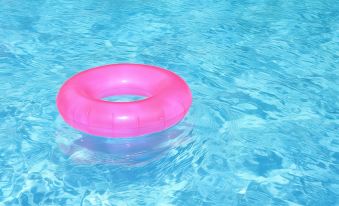 a pink inflatable ring floating in a swimming pool , surrounded by clear blue water at Hotel Kings Kudus