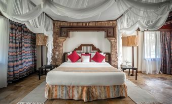 a large bed with a wooden headboard and white linens is surrounded by decorative pillows at Sarova Shaba Game Lodge