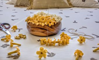 a wooden bowl filled with yellow flowers is placed on a bed next to a pillow at The Old Wailuku Inn at Ulupono