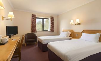 a hotel room with two beds , a window , and a desk , along with curtains and a chair at Days Inn by Wyndham Taunton