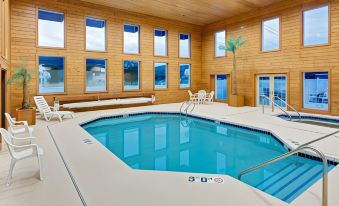 an indoor swimming pool surrounded by wooden walls , with several lounge chairs placed around the pool area at Ramada by Wyndham Richland Center