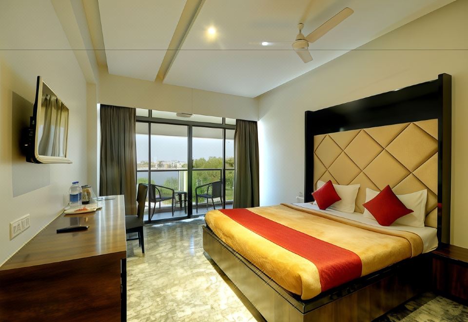 a modern bedroom with a large bed , wooden furniture , and a view of the outdoors through the window at Hotel Apaar