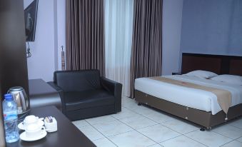 a bedroom with a bed , couch , and tv . also a dining table in the room at Griya Hotel