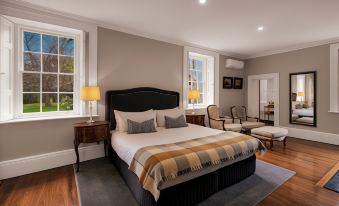 a large bed with a black headboard and white linens is situated in a bedroom next to two chairs at Quamby Estate