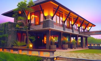 a large , modern house with wooden walls and a pool is lit up at night at Rumah Batu Boutique Hotel