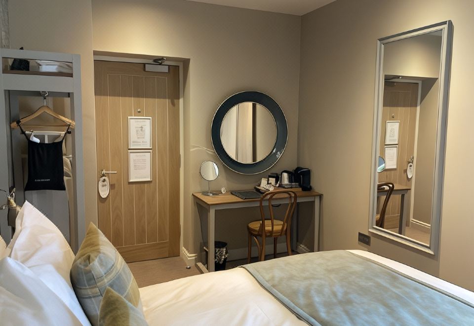 a hotel room with a bed , desk , and chair , as well as a door leading to another room at Old Swan