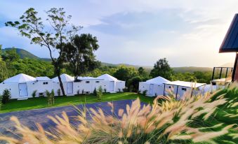 a group of white tents are set up in a field with trees in the background at Kirirath Resort