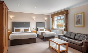 a hotel room with two beds , a couch , and a window , all decorated in a modern style at Burnley West Higher Trapp Hotel