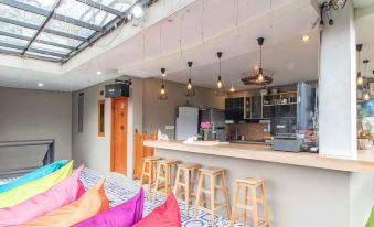 a modern kitchen with wooden stools , a bar area , and pendant lights , as well as a couch and a dining table at Van House