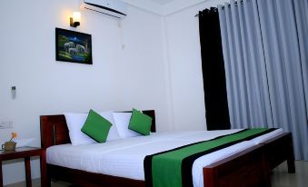 a bed with a green and white striped blanket and two green pillows is in a room with a window at Seasons Villa