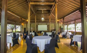 a large , open room with wooden beams and a white table surrounded by black chairs at Tlogo Resort & Goa Rong View Ungaran