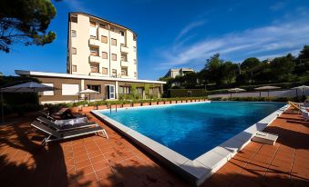 a large outdoor swimming pool surrounded by buildings , with several lounge chairs placed around the pool at Hotel Touring