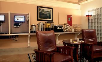 a brown leather chair is placed in front of a wall - mounted coffee maker and some books at Hotel Carmel Santa Monica