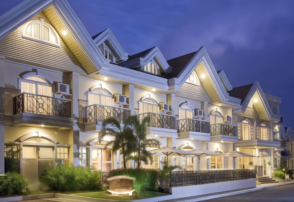 a row of white houses with balconies and lights on at night , surrounded by trees at Hotel Venezia