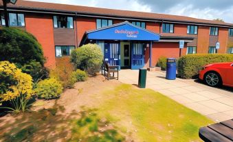 a small hotel with a blue awning and a table and chairs in front of it at Redwings Lodge Rutland