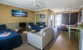 a modern hotel room with a bed , couch , tv , and dining table , as well as a view of the ocean at Iluka Motel