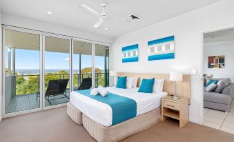 a large bedroom with a king - sized bed , two sliding glass doors leading to a balcony , and a view of the ocean at Akama Resort