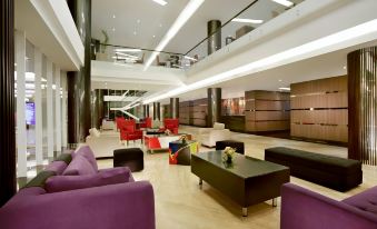 a modern hotel lobby with purple couches , black coffee tables , and large windows , creating an inviting atmosphere at Aston Kupang Hotel & Convention Center