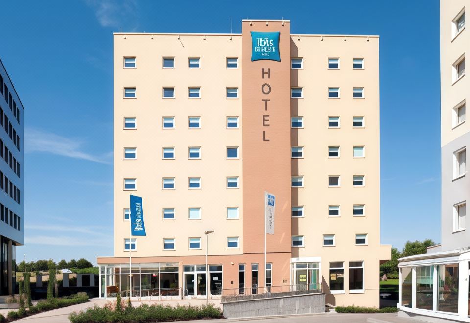 "a large hotel building with a sign that reads "" ibis suites "" prominently displayed on the front of the building" at Ibis Luxembourg Sud