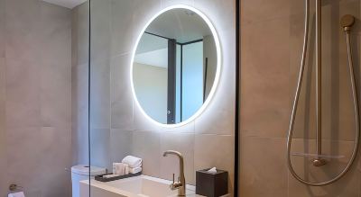 a bathroom sink with a round mirror and a faucet , along with some toiletries on the counter at Oval Hotel at Adelaide Oval, an EVT hotel
