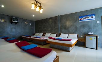 a modern hotel room with three beds , one of which is a bed with red and white bedding at Lampam Resort