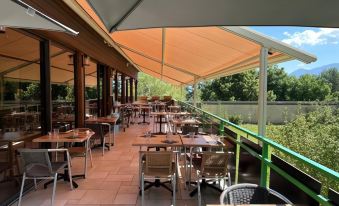 an outdoor dining area with a variety of tables and chairs under a large awning at Logis le Chalet