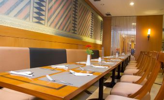 a dining room with a long table set for a meal , surrounded by chairs and a mural on the wall at Grand Pasundan Convention Hotel