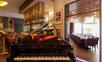 a grand piano is located in the middle of a room with large windows and tables at Steigenberger Braunschweig