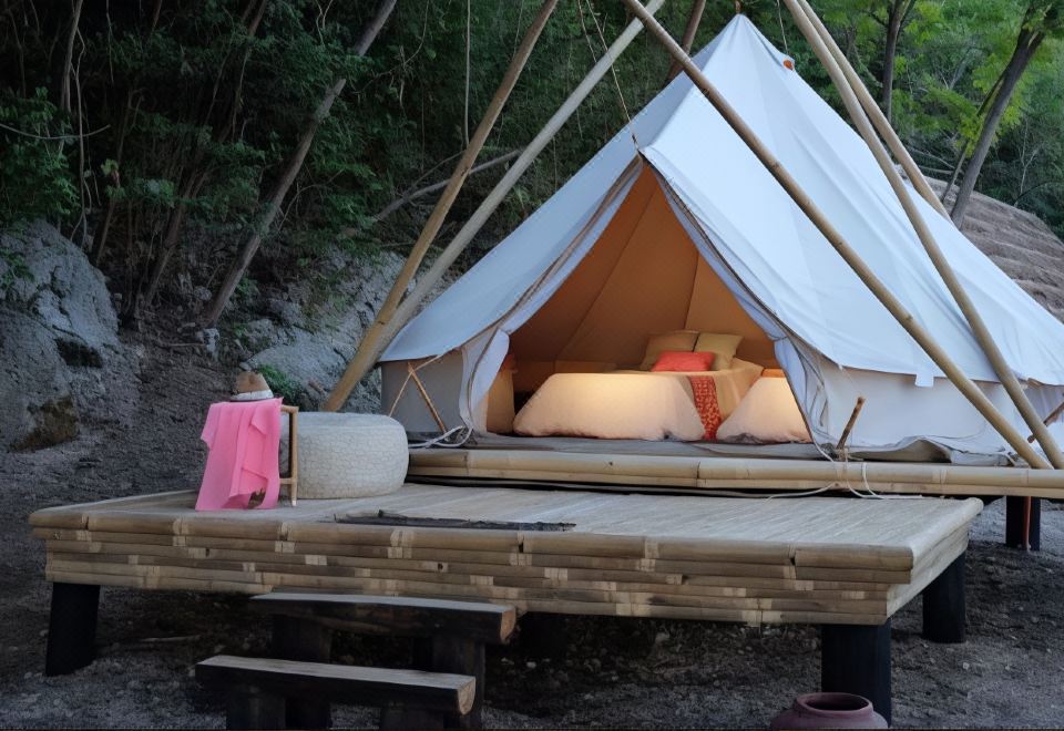 a large tent is set up on a wooden platform with two pillows and a pink suitcase nearby at Bluewater Sumilon Island Resort