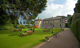 a large house with a red roof is surrounded by green grass and trees , with benches in front of it at St Andrews Town Hotel