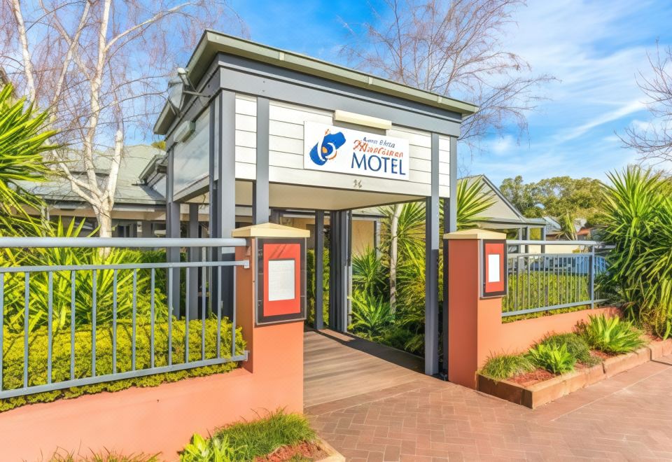 "a modern , multi - story building with a white facade and red columns , surrounded by greenery and trees , and featuring a sign reading "" our" at Berry Village Boutique Motel