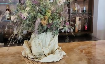 a bouquet of flowers sits on a bar counter in front of a window , surrounded by bottles and glasses at Hotel Amelia