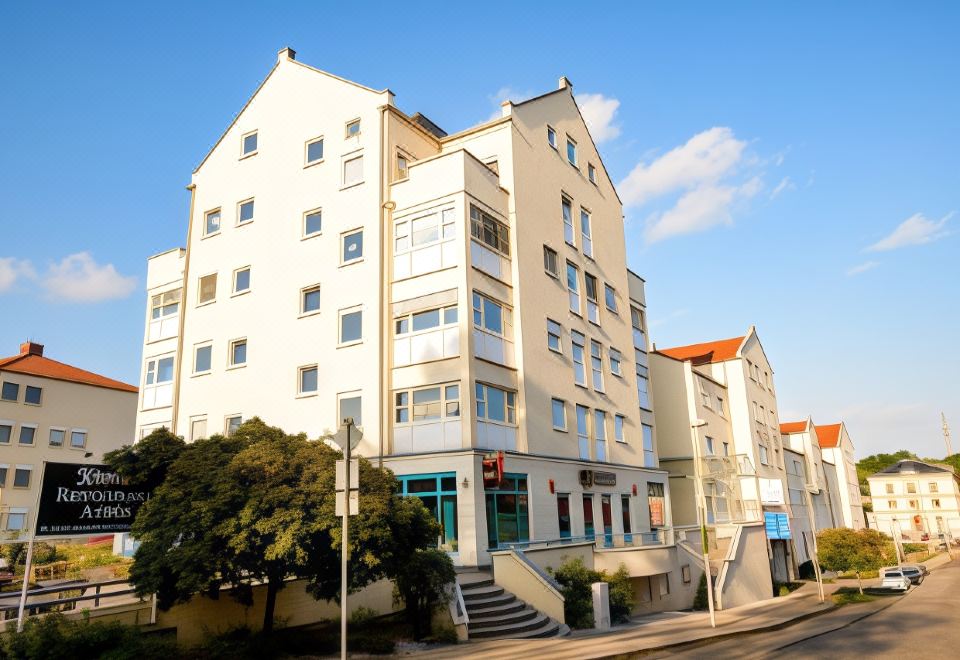 a modern , white apartment building with multiple floors and balconies , situated on a street corner under a clear blue sky at Hotel Astor