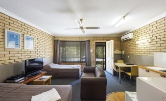 a modern living room with exposed brick walls , wooden furniture , and a large window that overlooks a balcony at Iluka Motel