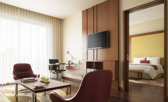 a modern living room with a large flat - screen tv mounted on the wall , surrounded by comfortable furniture at Courtyard Kochi Airport