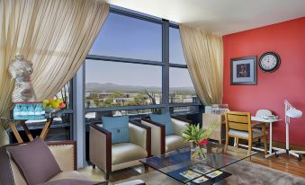 a living room with a large window and a view of the mountains , featuring two chairs and a table at Hilton Windhoek