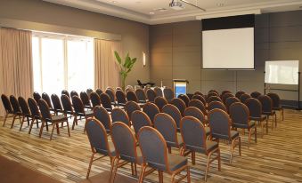 a large conference room with rows of chairs arranged in a semicircle , and a projector mounted on the wall at Pacific Bay Resort