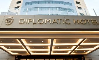 "the entrance to a hotel named "" diplomatic hotel "" with its sign and a large , modern building in the background" at DiplomaticHotel