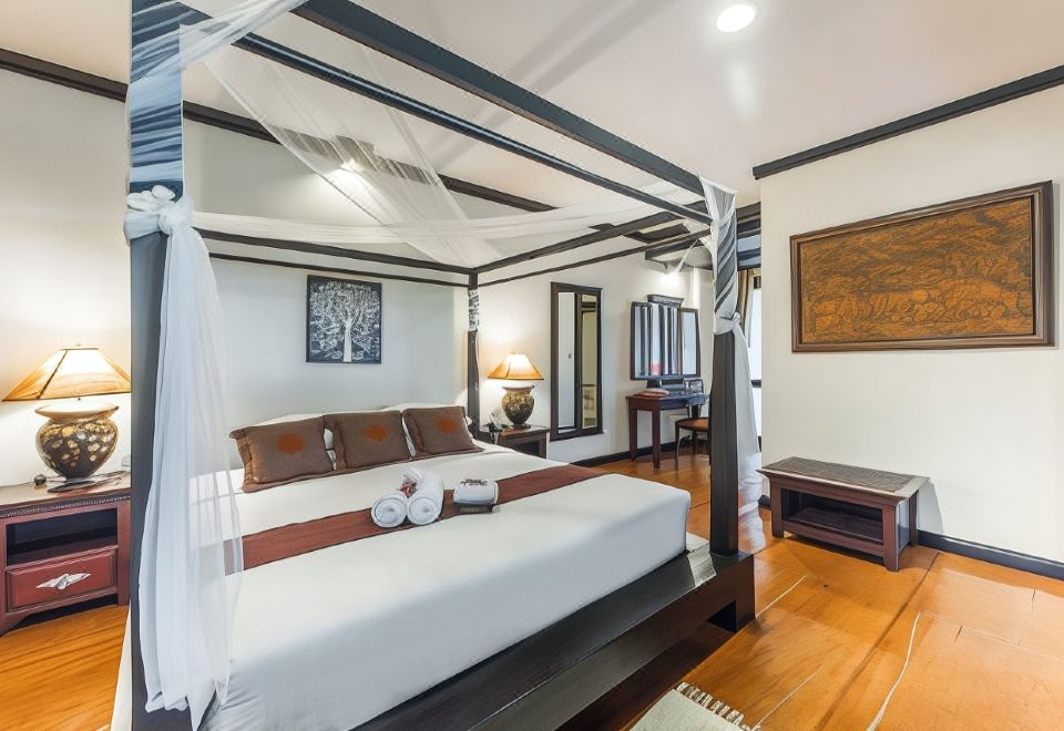 a large bed with a canopy is in a room with wooden floors and walls at Gassan Khuntan Golf & Resort
