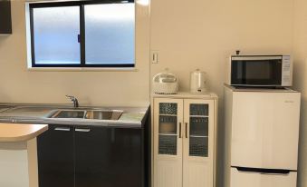 a kitchen with a sink , microwave , and refrigerator , along with cabinets and a window at Cottage Sunset-Village