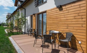 a wooden deck with several chairs and tables set up for outdoor dining , creating a pleasant atmosphere at Colors Apartments