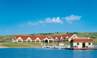 a large building with a red roof and white trim is situated on the shore of a body of water at Arrowwood Resort at Cedar Shore