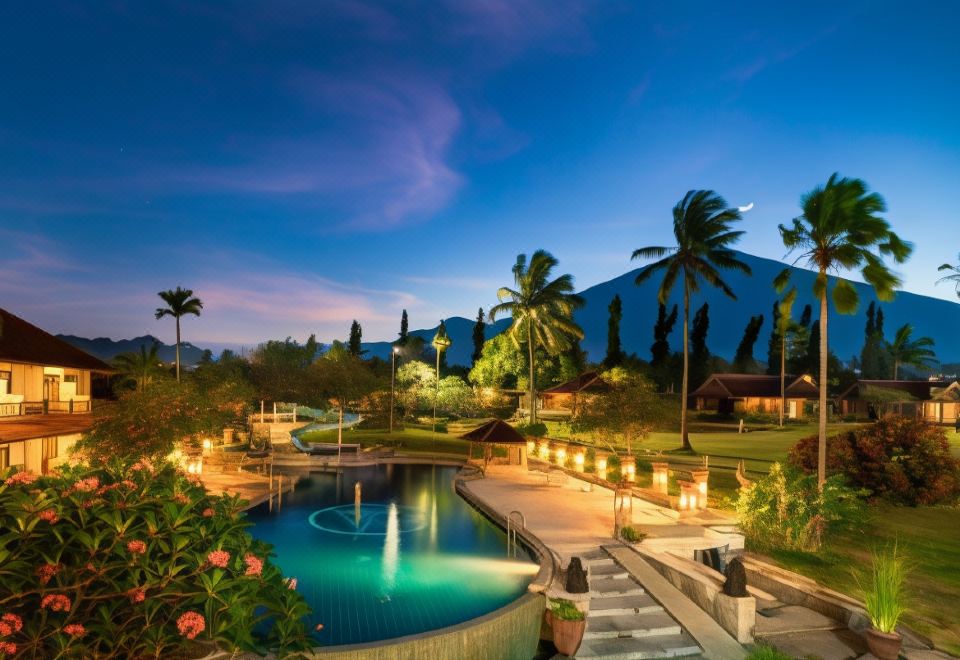 a beautiful resort with a large pool surrounded by palm trees , mountains in the background , and a fountain in the foreground at Horison Tirta Sanita Spa Resort